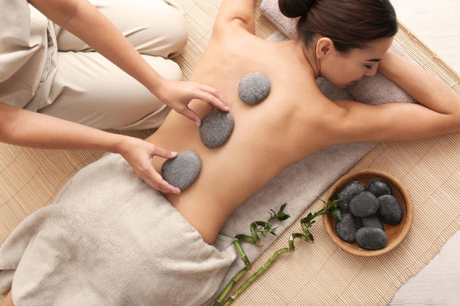 Een jonge vrouw geniet van een hot stone massage bij Santé Magic te Leuven.